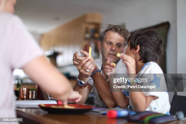 a family snacking on potato chips while sitting around the table at home. - 繼父 個照片及圖片檔