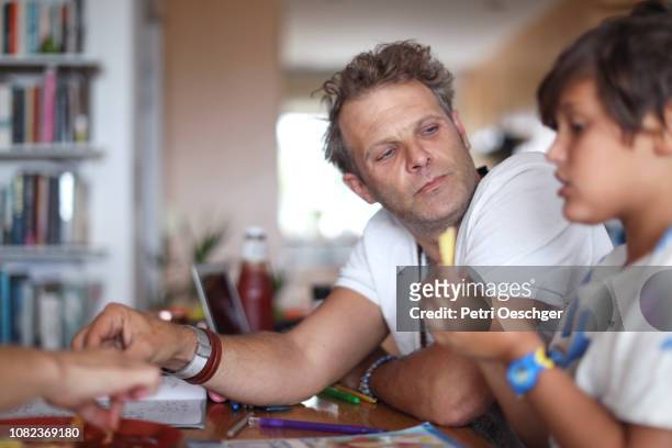 a family snacking on potato chips while sitting around the table at home. - family eating potato chips imagens e fotografias de stock
