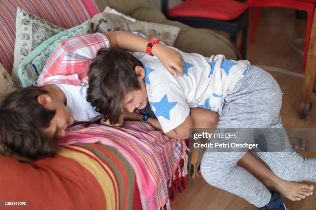 Twin sisters playfully roughhousing at home.