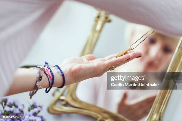 schmuck - frau vor spiegel mit ketten und armbändern - bijou fotografías e imágenes de stock