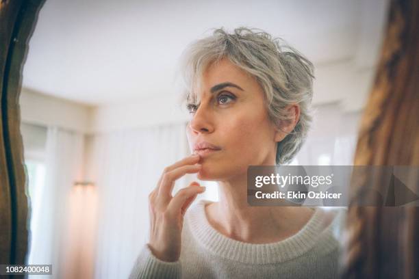 gray haired woman by the mirror - cabello gris fotografías e imágenes de stock