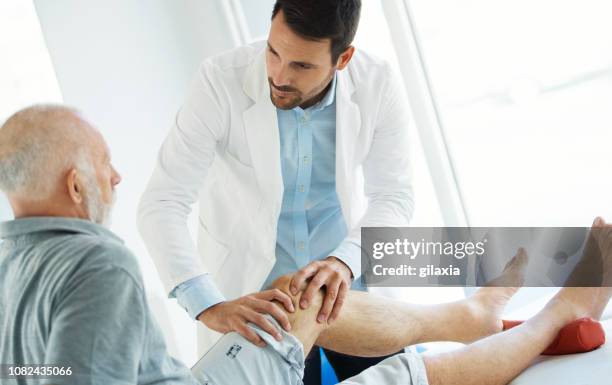 ältere mann mit seinem knie von einem arzt untersucht. - osteoporose stock-fotos und bilder