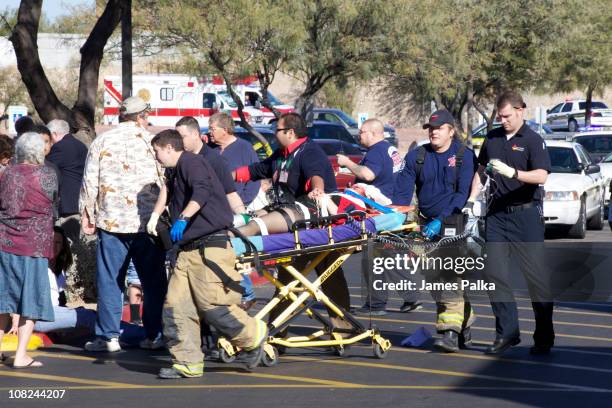 Emergency personnel and Daniel Hernandez , an intern for U.S. Rep. Gabrielle Giffords , move Giffords after she was shot in the head outside a...