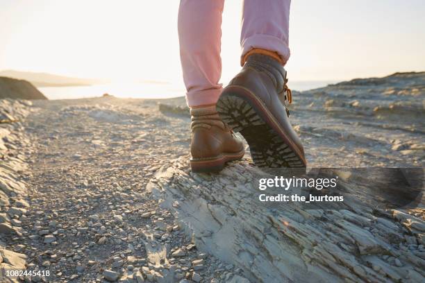 woman in hiking boots standing on a rock - female soles stockfoto's en -beelden