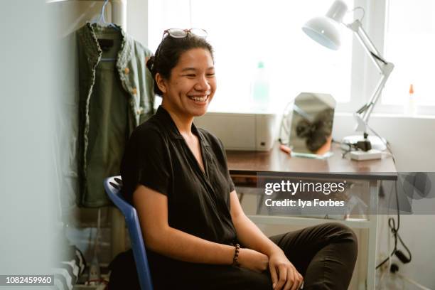 young filipino student sitting in her dorm room - filipino stockfoto's en -beelden