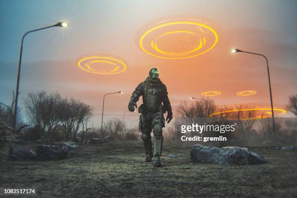 cyborg futuristico che cammina nel deserto con ufo volanti - personaggio foto e immagini stock