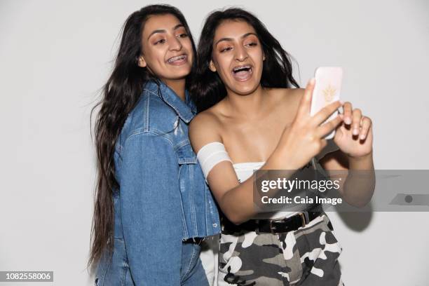 teenage twin sisters taking selfie with smart phone - asian twins stockfoto's en -beelden