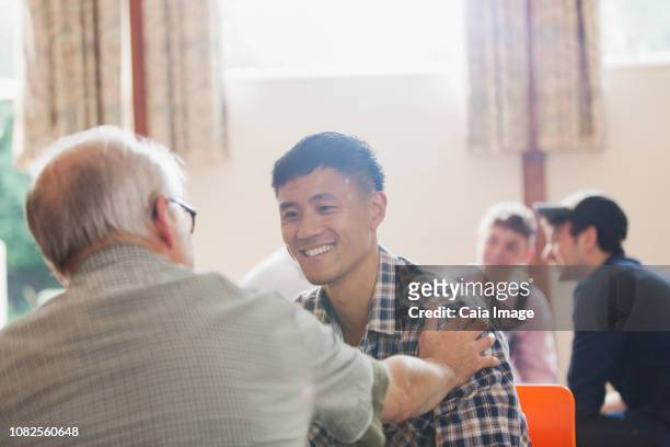smiling men talking in community center - promises rehab center bildbanksfoton och bilder