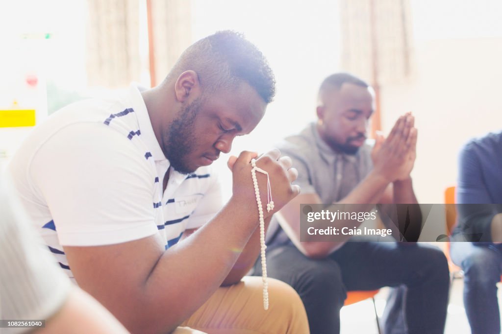 Man praying with prayer beads in prayer group