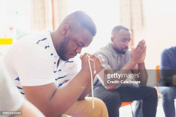 Man praying with prayer beads in prayer group