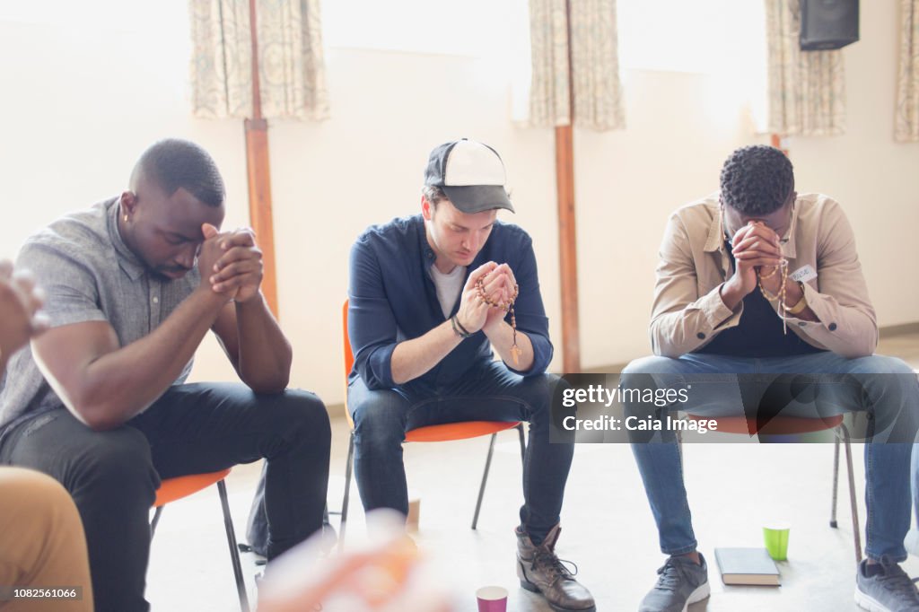 Men praying with rosaries in prayer group