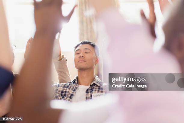 serene man praying with arms raised in prayer group - trust god stock pictures, royalty-free photos & images