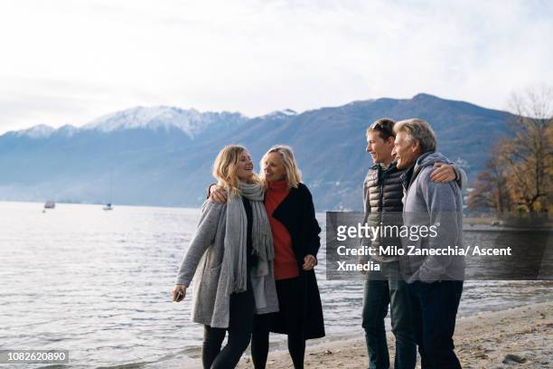 family have playful conversation at lake edge - lakeshore stockfoto's en -beelden