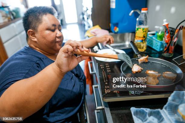 differently abled filipino woman cooking at home - daily life in philippines stockfoto's en -beelden