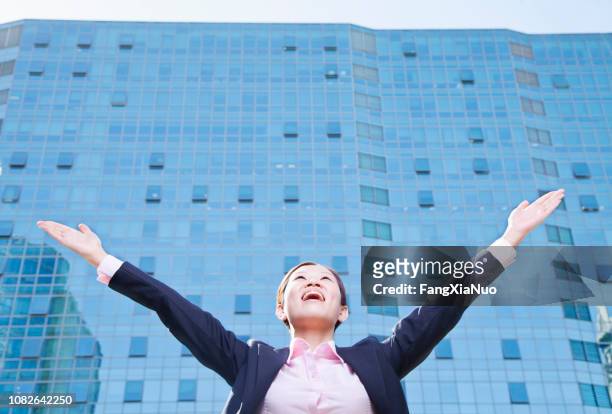 empresaria de china con los brazos extendidos frente a rascacielos - easy solutions fotografías e imágenes de stock