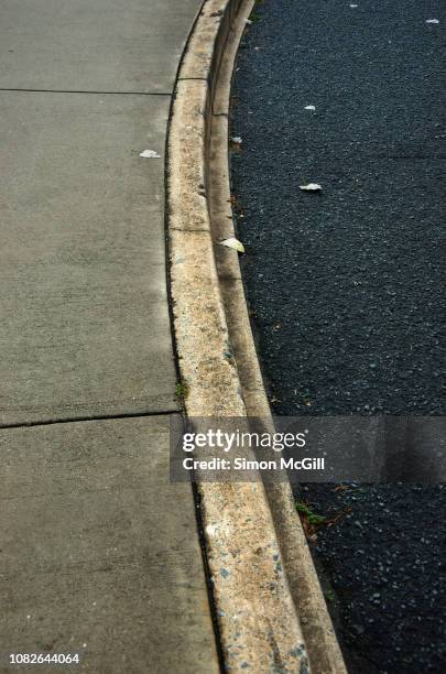 concrete footpath, curb and asphalt road - rinnsteinkante stock-fotos und bilder