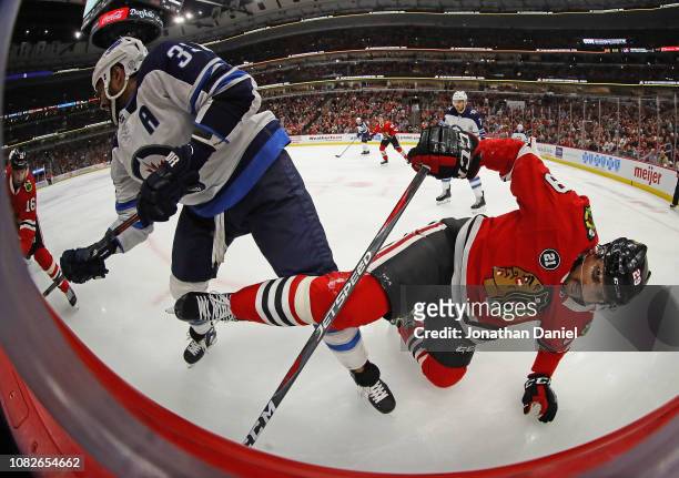 Andreas Martinsen of the Chicago Blackhawks hits the ice while battling with Dustin Byfuglien of the Winnipeg Jets at the United Center on December...