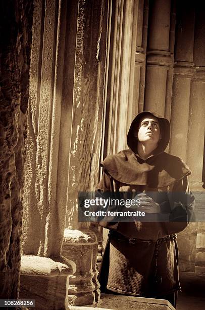 monk praying in cloister of church, sepia toned - nun habit stock pictures, royalty-free photos & images