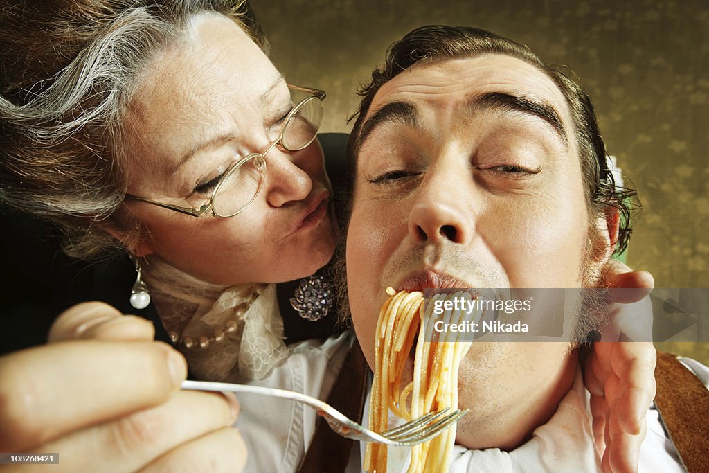 Overzealous Mother Feeding Adult Son Pasta