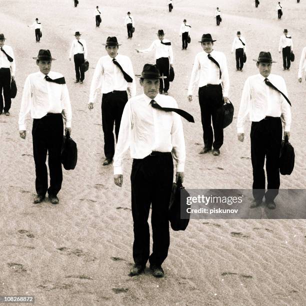 group of similiar men standing on sand - cloning stock pictures, royalty-free photos & images