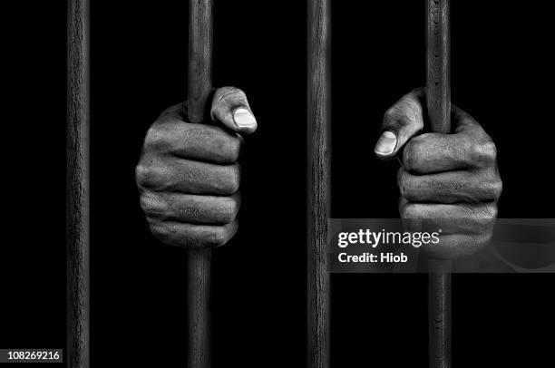 hands of a prisoner on prison bars - prison stockfoto's en -beelden