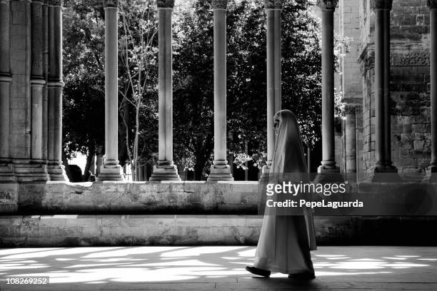 monja caminando a través de una iglesia habitación cloister, blanco y negro - nun fotografías e imágenes de stock
