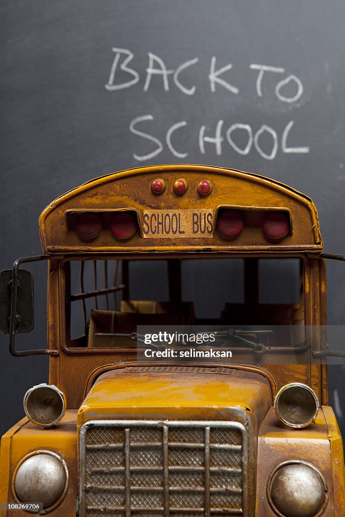 School Bus before blackboard with back to school text on