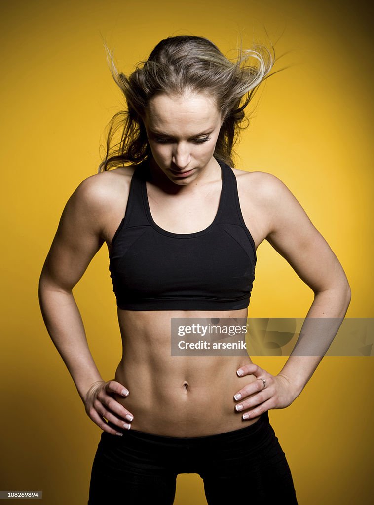 筋肉の若い女性エクササイズ用ウェア、絶縁に黄色