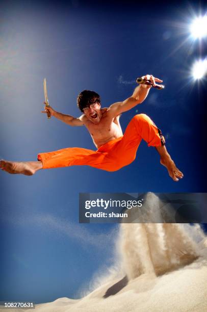 ninja man jumping on beach and kicking sand - ninja weapon stock pictures, royalty-free photos & images