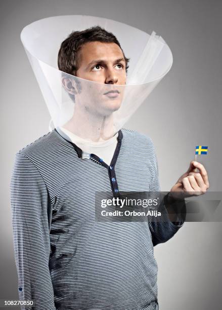 man wearing dog cone holding mini swedish flag - hondenkraag stockfoto's en -beelden