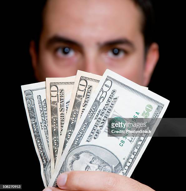 mann in schwarz versteckt sich hinter geld - aufgefächert stock-fotos und bilder