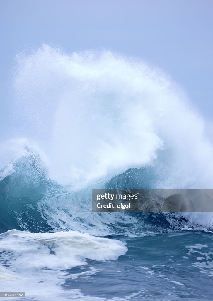 Exploding Wave with white spray and blue clear sky background