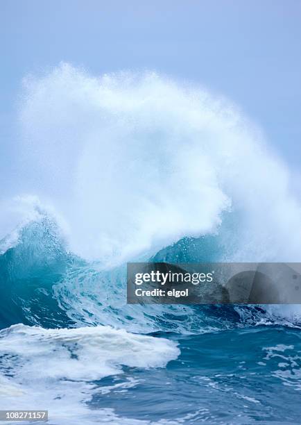 exploding wave with white spray and blue clear sky background - tsunami stock pictures, royalty-free photos & images