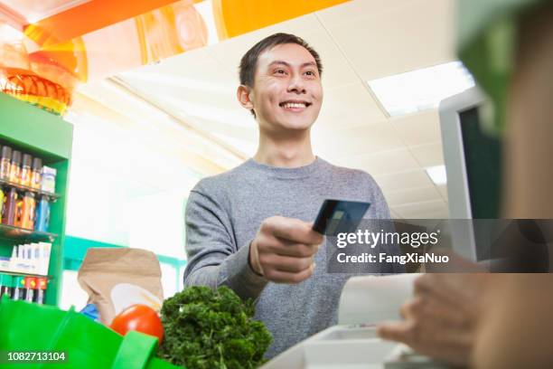 chinesischen kunden übergeben kreditkarte kasse im supermarkt - bonuskarte stock-fotos und bilder