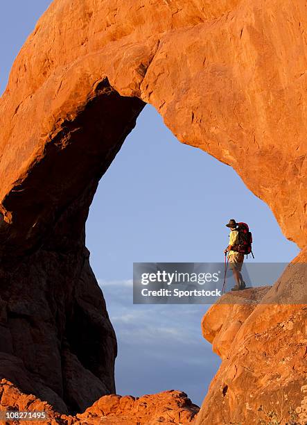 hiker standing on high rocky ledge in arches national park - moab utah stockfoto's en -beelden