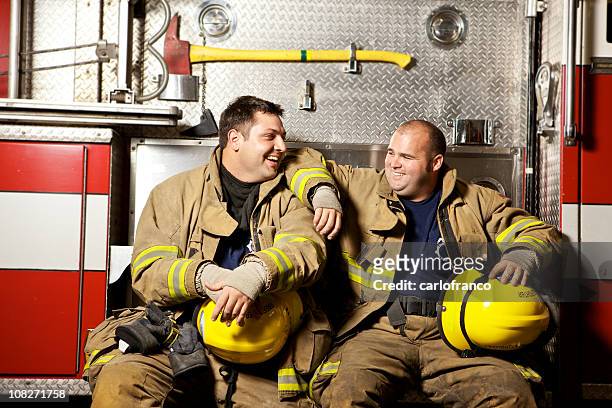 two firefighters in gear sitting on side of truck - fireman axe stock pictures, royalty-free photos & images