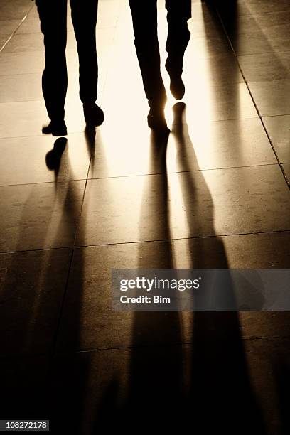 silhouettes and shadows of two businessman walking in corridor - 2 businessmen in silhouette stock pictures, royalty-free photos & images