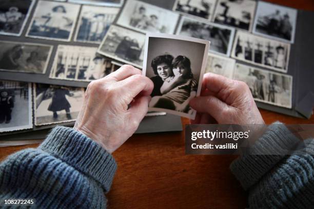 elderly hands looking at old photos of self and family - souvenir bildbanksfoton och bilder