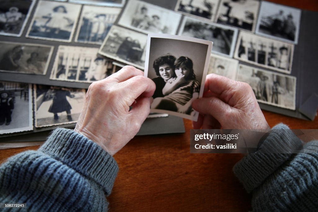 Elderly hands looking at old photos of self and family