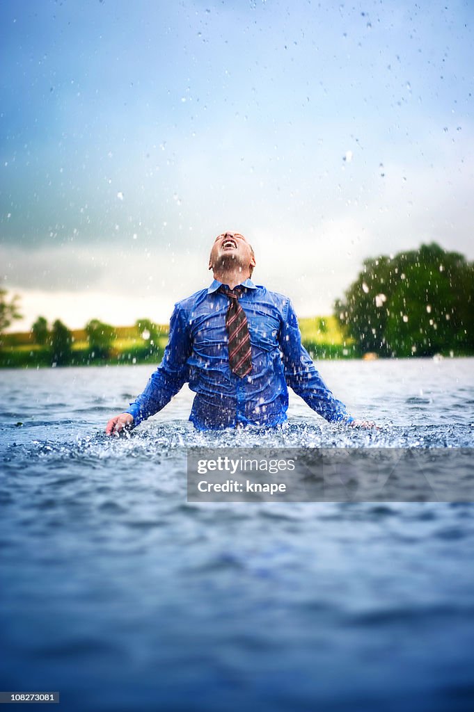 Businessman enjoying rain in a lake