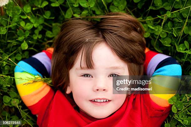 kleines mädchen im gras liegen - rainbow kids stock-fotos und bilder