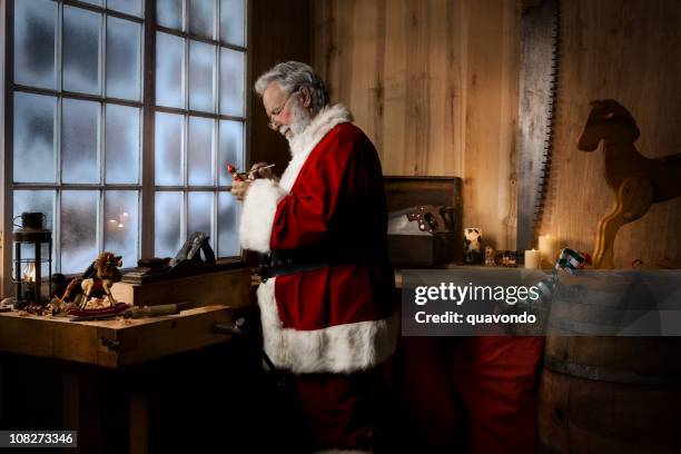 christmas santa claus working in his toy workshop, copy space - santas workshop stock pictures, royalty-free photos & images