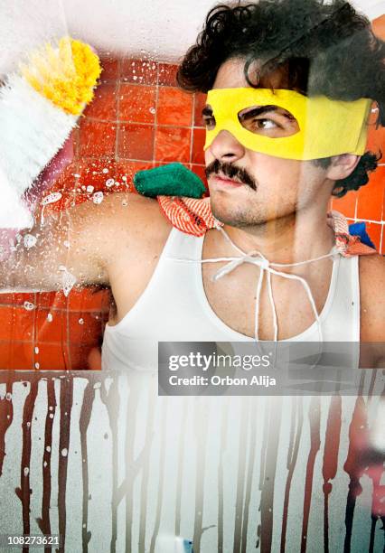 man wearing superhero mask scrubbing shower tiles - housework humour stock pictures, royalty-free photos & images