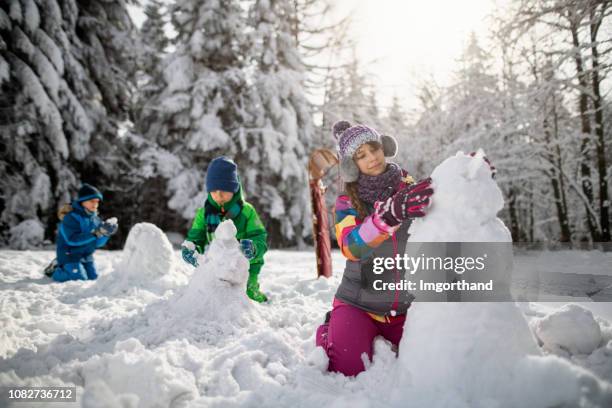 kids building snowmen on a winter day - making a snowman stock pictures, royalty-free photos & images