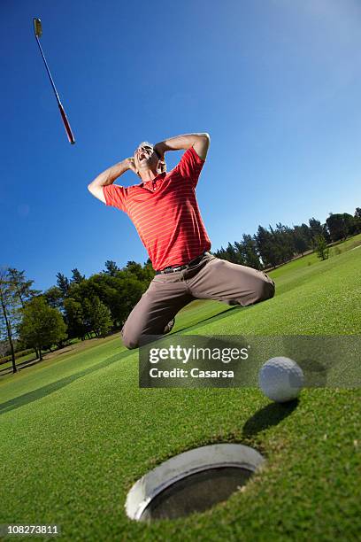 golfer yelling and throwing golf club with ball beside hole - angry golfer stock pictures, royalty-free photos & images