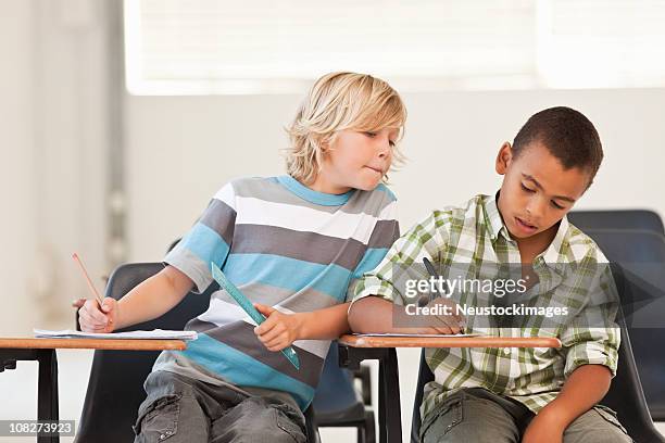 little boy peeping in classmates examination paper - deception stockfoto's en -beelden