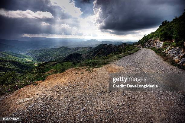 view of road through green mountains on a cloudy day - ominous mountains stock pictures, royalty-free photos & images