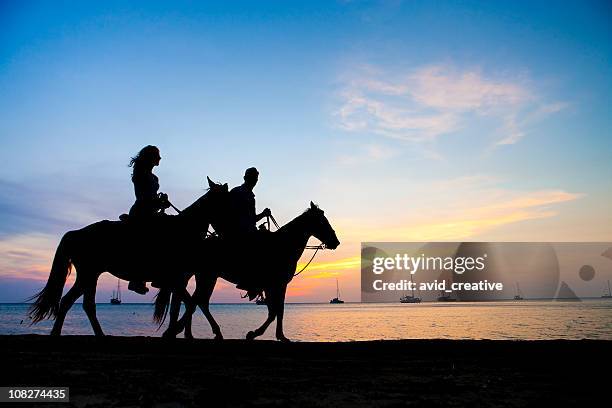 vacation lifestyles-couple horseback riding at sunset - recreational horseback riding stock pictures, royalty-free photos & images