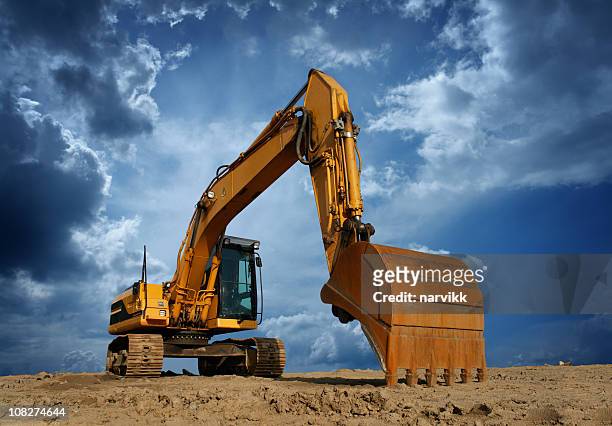amarillo excavator en solar de construcción - máquina excavadora fotografías e imágenes de stock