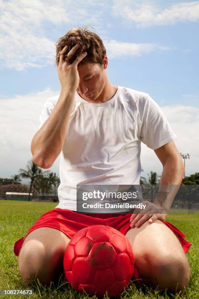 male soccer player kneeling in field with ball - defeat stock pictures, royalty-free photos & images